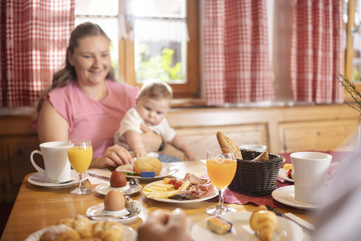 Familie sitzt an einem gedeckten Frühstückstisch