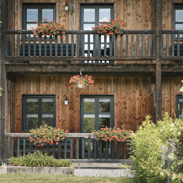 Haus mit Holzfassade und bepflanzten Balkonen