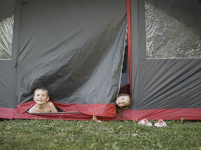 Zwei Kinder schauen aus einem Zelt