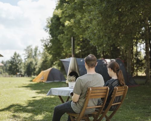 Ein Pärchen sitzt an einer Tischgruppe auf dem Campingplatz und blickt ins Grüne